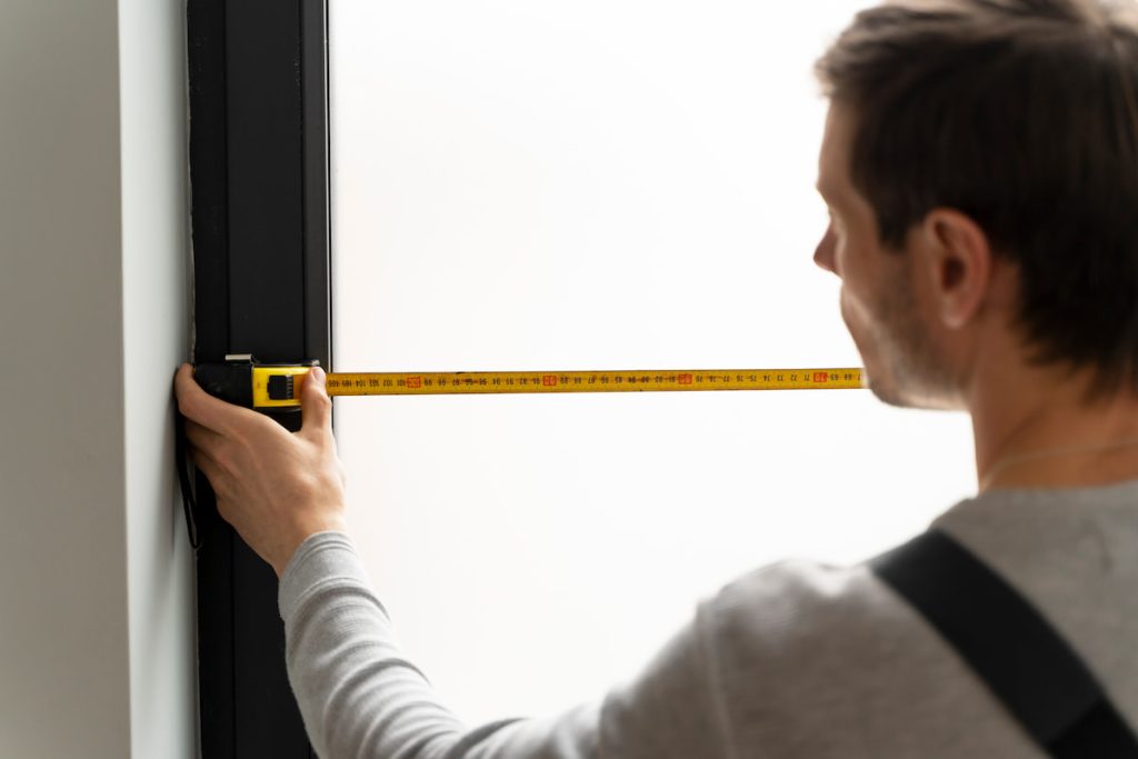 Profesional midiendo un hueco en la pared para comprobar las medidas estandar ventanas pvc antes de la