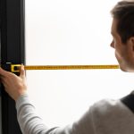 Profesional midiendo un hueco en la pared para comprobar las medidas estandar ventanas pvc antes de la